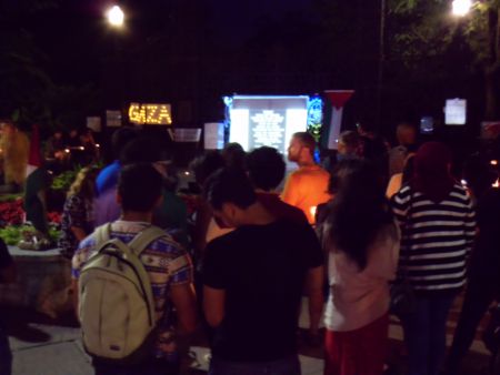 People at the vigil watch the slideshow on the screen
