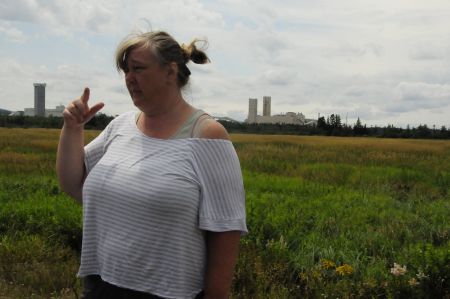 Beth Nixon stands on the McLeod family farm, affected by subsidence. Potash mine in background.