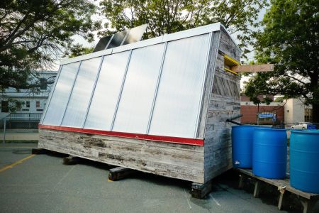 The Bloomfield Greenhouse in Halifax is portable and manages its own water, electric and heating needs entirely off the grid. Its parabolic shape points south and brings sunlight through insulated glass and onto a thermal mass of waist-high soil lined with bricks and an earth-plastered wall. An airlock double door to the north acts as further insulation. In midwinter when temperatures can reach -20C the greenhouse can sustain salad greens at a comfortable +5C through the sun alone. Photo EAC