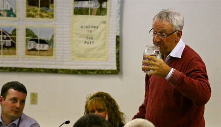 5 million ways to kill a CEO? Peter Hill takes a long draught from a tall glass of 'treated' frack waste water, while Environment minister Randy Delorey looks on. [Photo: Miles Howe]