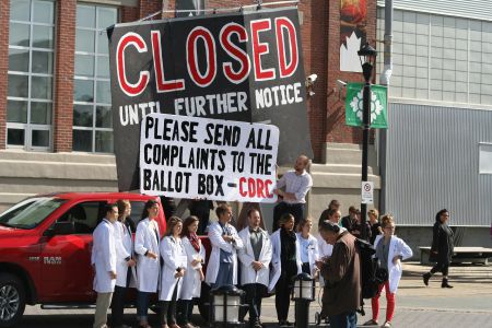 When voting in the upcoming election people should remember refugee healthcare cuts, say Halifax physicians and medical students. That's why they briefly blocked the entrance to Pier 21, one of Canada's best known immigration landmarks. Photo Robert Devet   