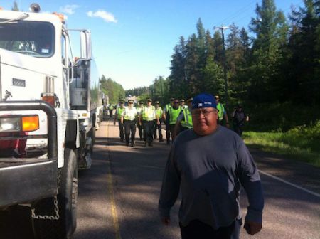 John Levi from Elsipogtog walks in front of RCMP officers who have blocked Highway 126 on June 5th. Photo by Fabien Peters.