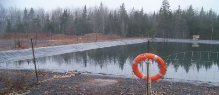 Frack waste pond in Kennetcook. NS Environment tells the community it is monitoring the ponds. But they are supposed to have 1 metre [39"] of freeboard. There is now less than 12 inches between the surface and overflow, with freeze-up and winter precipitation to add. There are holes in the pond liner right at the water level. Leaks there will flow through the berm above the surrounding ground level.