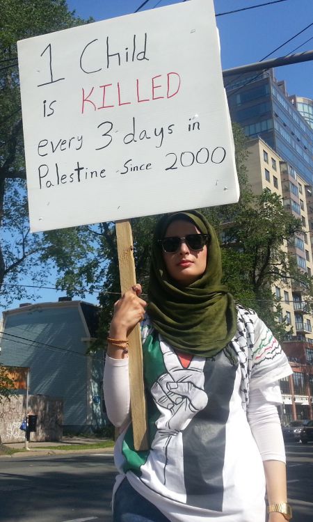 A member of Students Against Israeli Apartheid Dalhousie protests on Tuesday.  The sign says, "One child is killed every 3 days in Palestine since 2000."