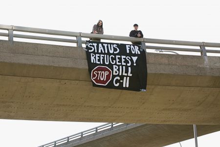 Members of No One Is Illegal defend refugee rights with a banner hung from an overpass. Photo by Hilary Beaumont
