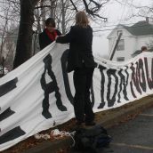 Volunteers help to string up a banner that says Climate Action Now.