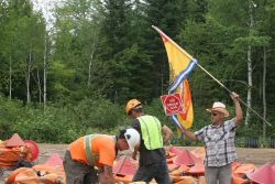 Activists and industry. While SWN-contracted workers load geo-phone bags, one man waves New Brunswick flag. [Photo: M. Howe]